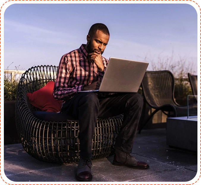 A man sitting on top of a chair using his laptop.