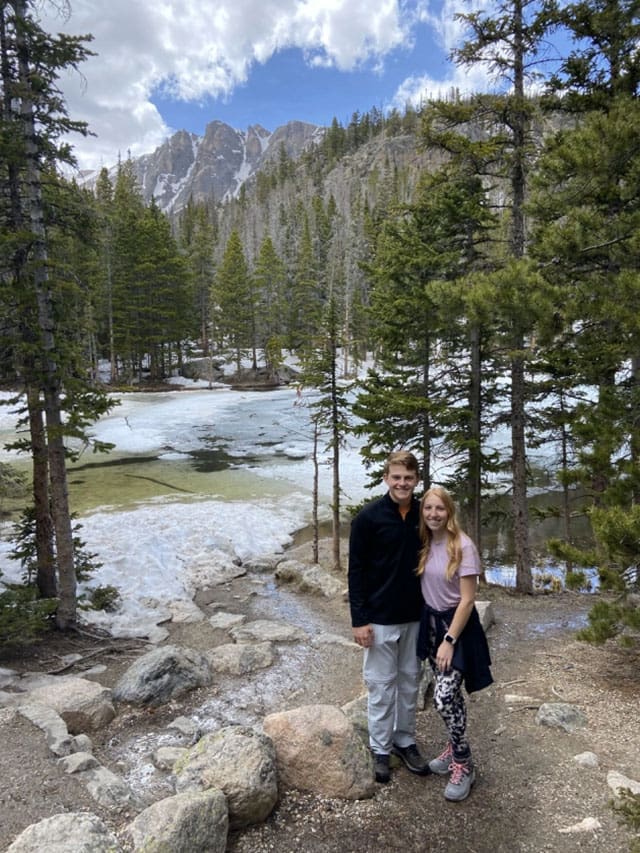 Couple posing by a snowy mountain lake.