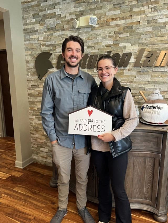 Couple holding "we said yes to the address" sign.