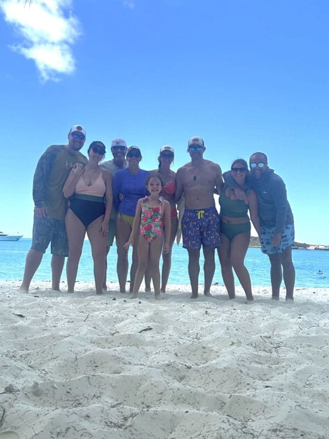 Group of people posing on a beach.